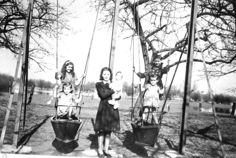 Agnes (jes) Hamans-Schmitz met Chris (CJG) Hamans op de arm. In de schuitjes van de schommel, de tweeling Chris en Mieke Ramakers. Op de achtergron nog restant van ondergelopen weiland door hoogwater?  Voorjaar 1947